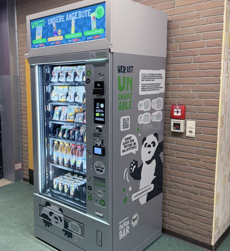 unshakeable-Snackautomat an einer Wand im Innenbereich, gefüllt mit Bio-Snacks und Getränken